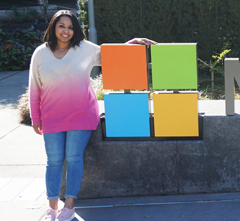 Cassandra smiling for the camera beside a Microsoft sign.