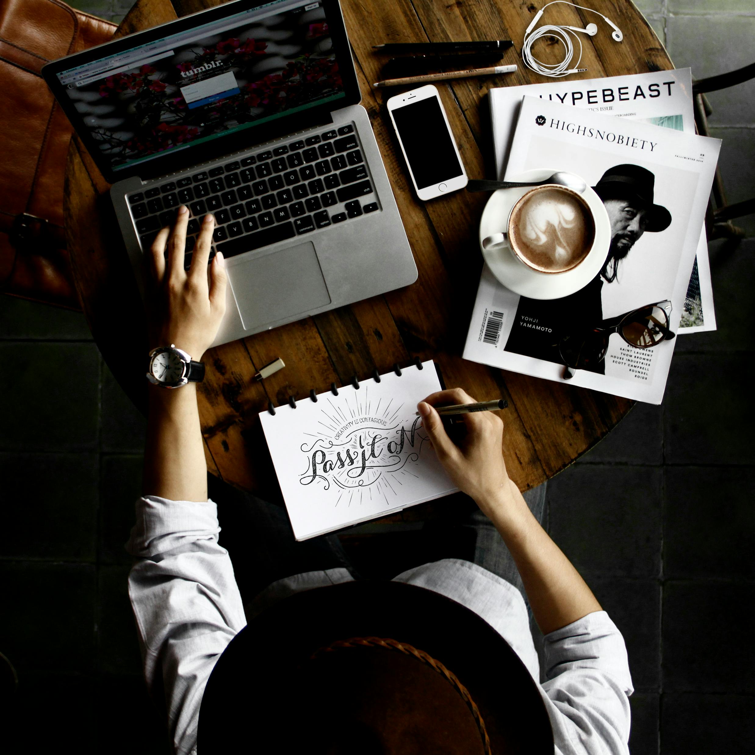 Designer sitting and working on notepad and laptop.